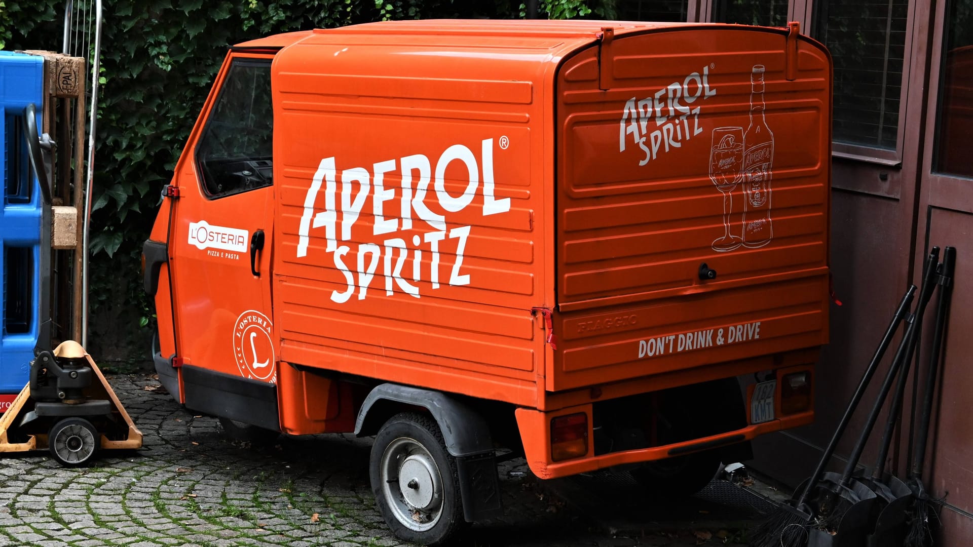 Werbemotiv: Ein Ape von Piaggio im Innenhof einer Pizzeria.