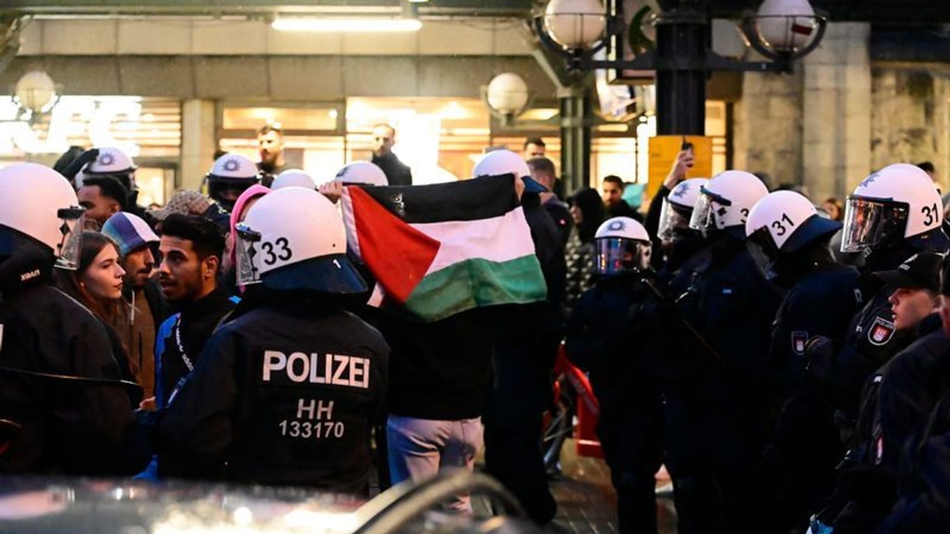 Teilnehmer einer pro-palästinensischen Kundgebung vor dem Hauptbahnhof tragen palästinensische Flaggen: Trotz Verbots der Veranstaltung versammelte sich eine Gruppe von Demonstranten, die Polizei reagierte mit Festnahmen.
