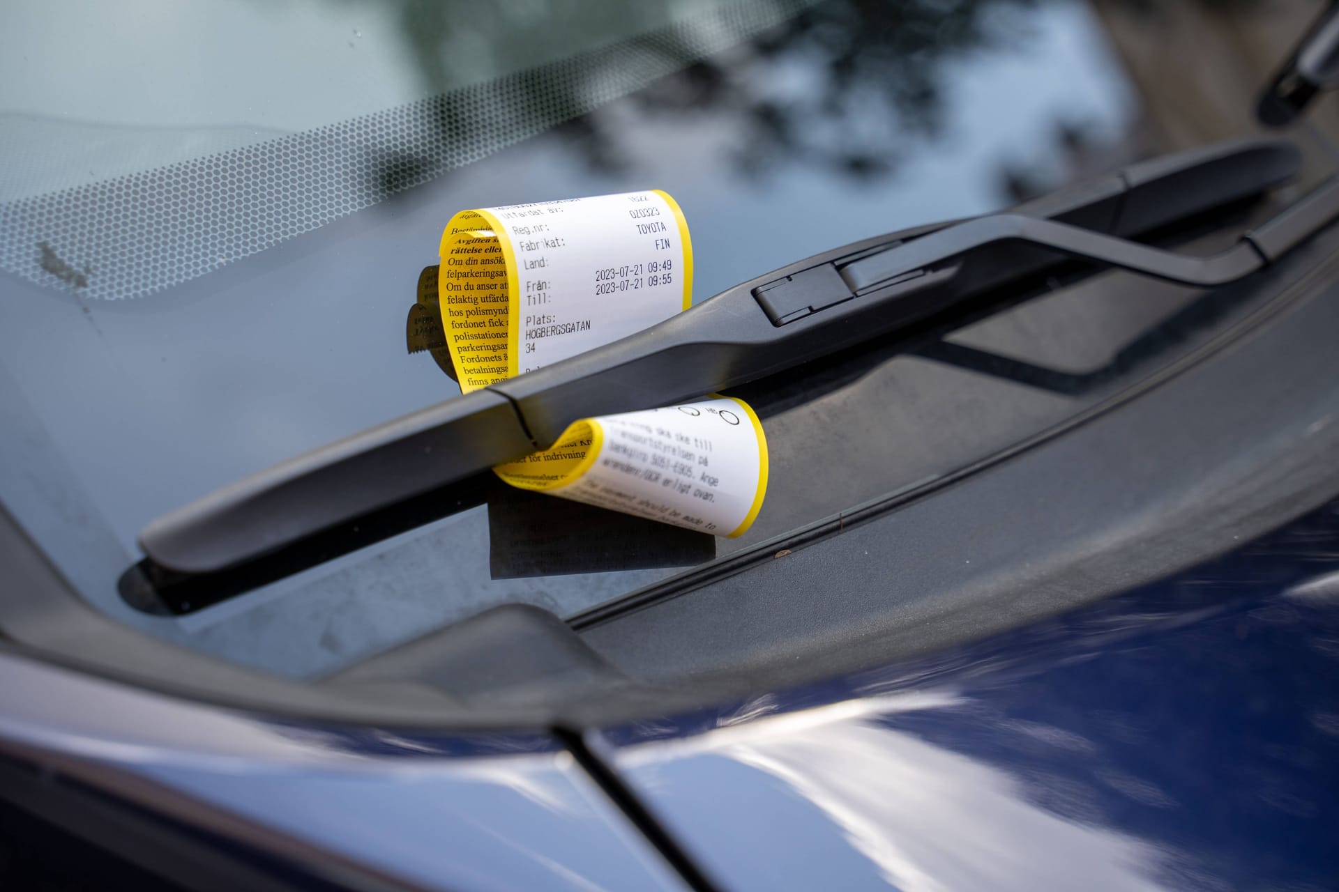 Ein Strafzettel am Scheibenwischer eines Autos. Strafe für Falschparken (Symbolbild).