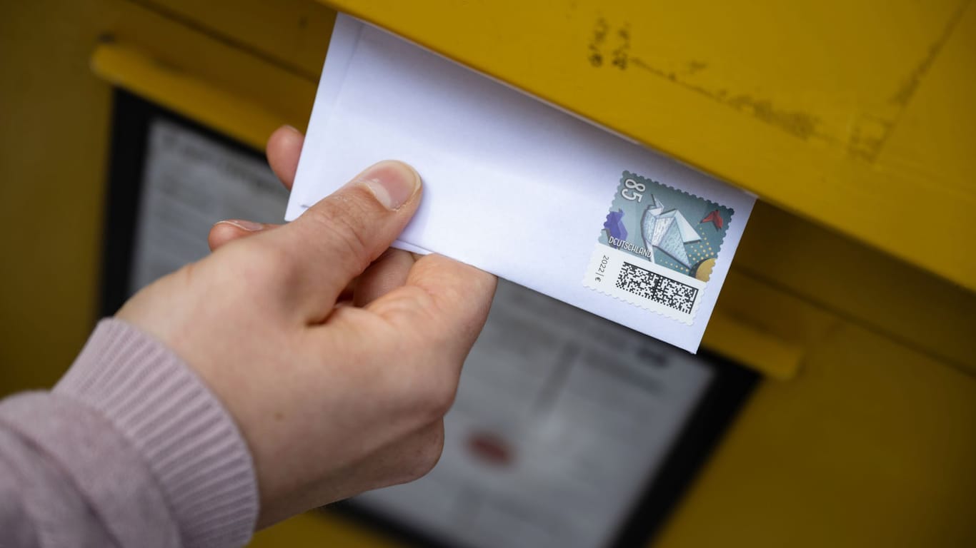Person steckt einen Brief in einen Briefkasten