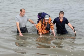 Zwei Retter haben den Urlauber ausgegraben und in ihre Mitte genommen: Der Urlauber stimmte der Veröffentlichung des Bildes zu, um andere auf die Gefahren des Wattenmeeres hinzuweisen.