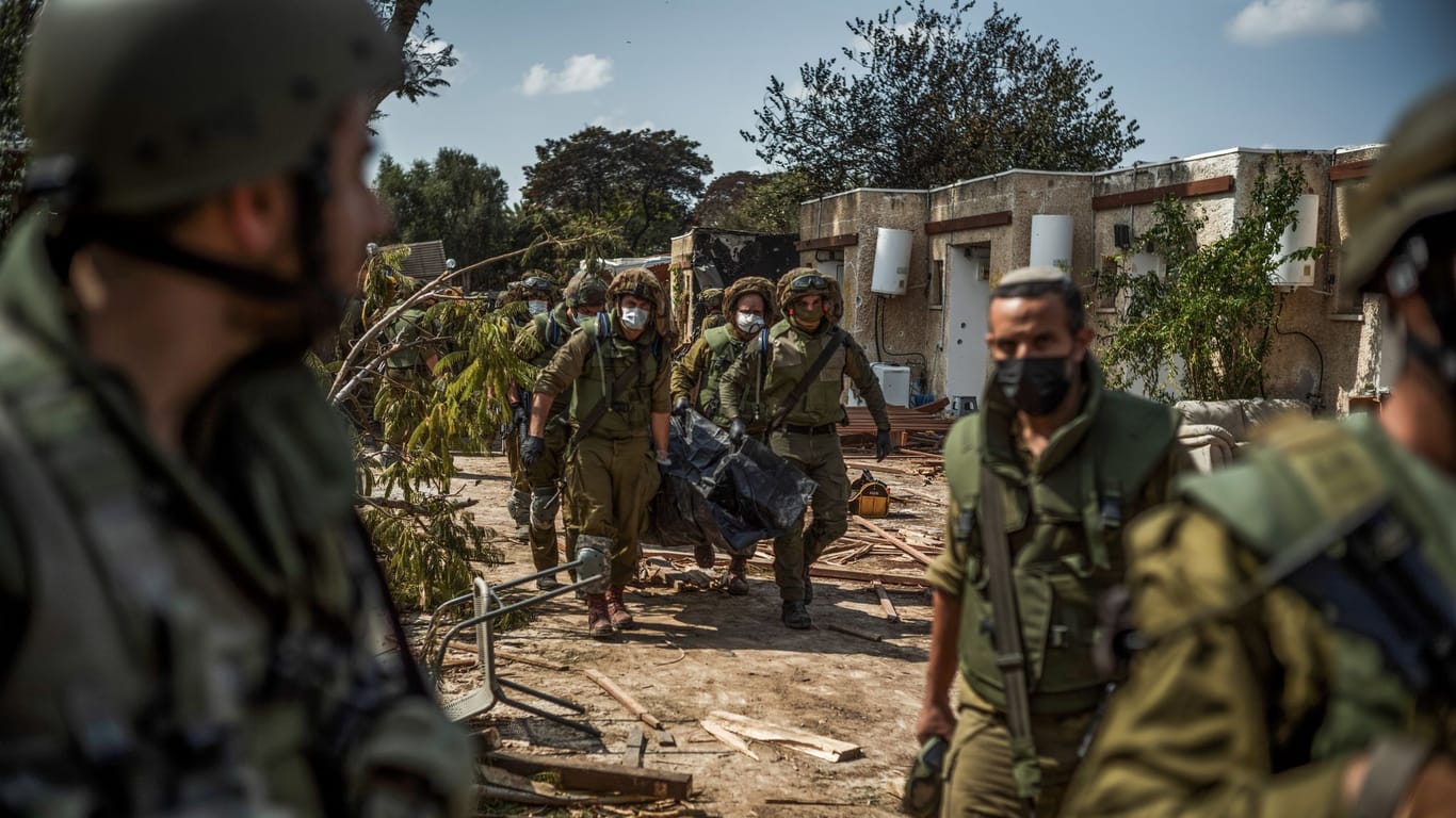 Israelische Streitkräfte bergen Leichen von israelischen Bewohnern aus einem zerstörten Haus.