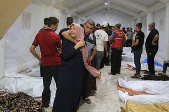 Palästinenser stehen in einem Krankenhaus neben Opfern israelischer Luftangriffe (Archivbild): Um die Zahl der Toten wird gestritten.