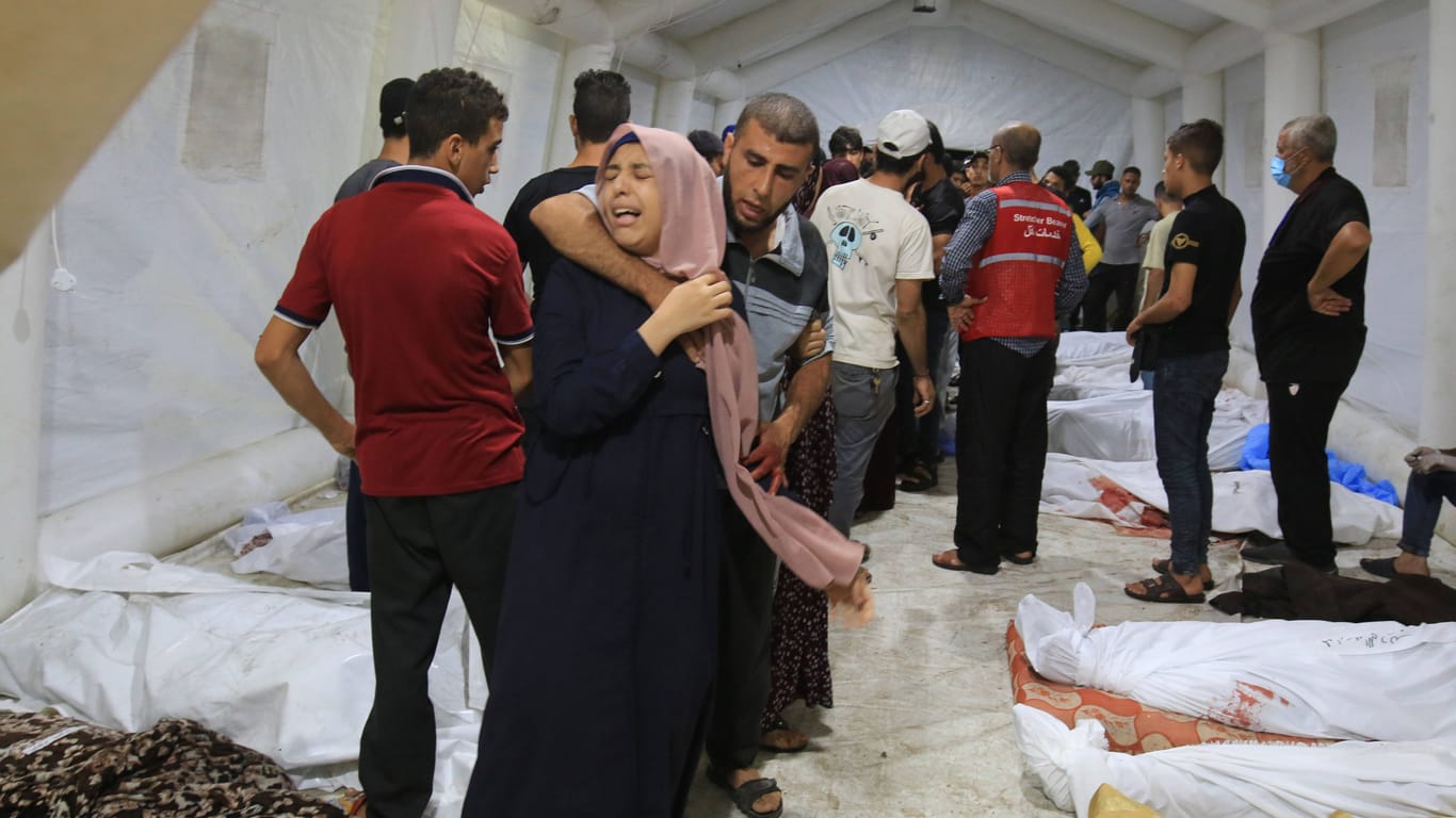 Palästinenser stehen in einem Krankenhaus neben Opfern israelischer Luftangriffe (Archivbild): Um die Zahl der Toten wird gestritten.