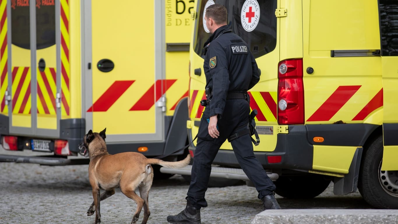 Polizist läuft mit Hund vor Krankenwägen: Drohungen gegen eine Schule in Sachsen haben den Sprengstoffspürhund auf den Plan gerufen.