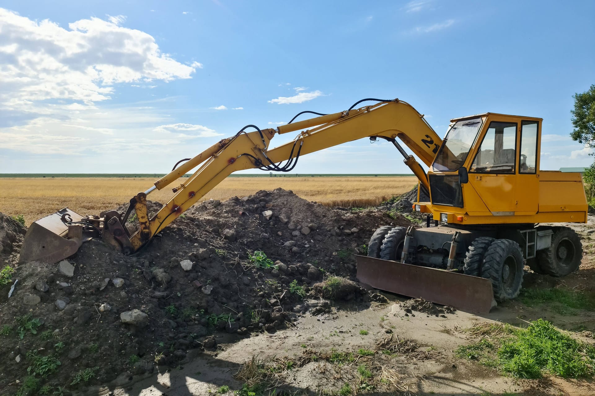 Ein Bagger auf einem Feld (Symbolbild): Die Bauarbeiten ruhen nun erst einmal, bis Mitte 2024 wird archäologisch geforscht.