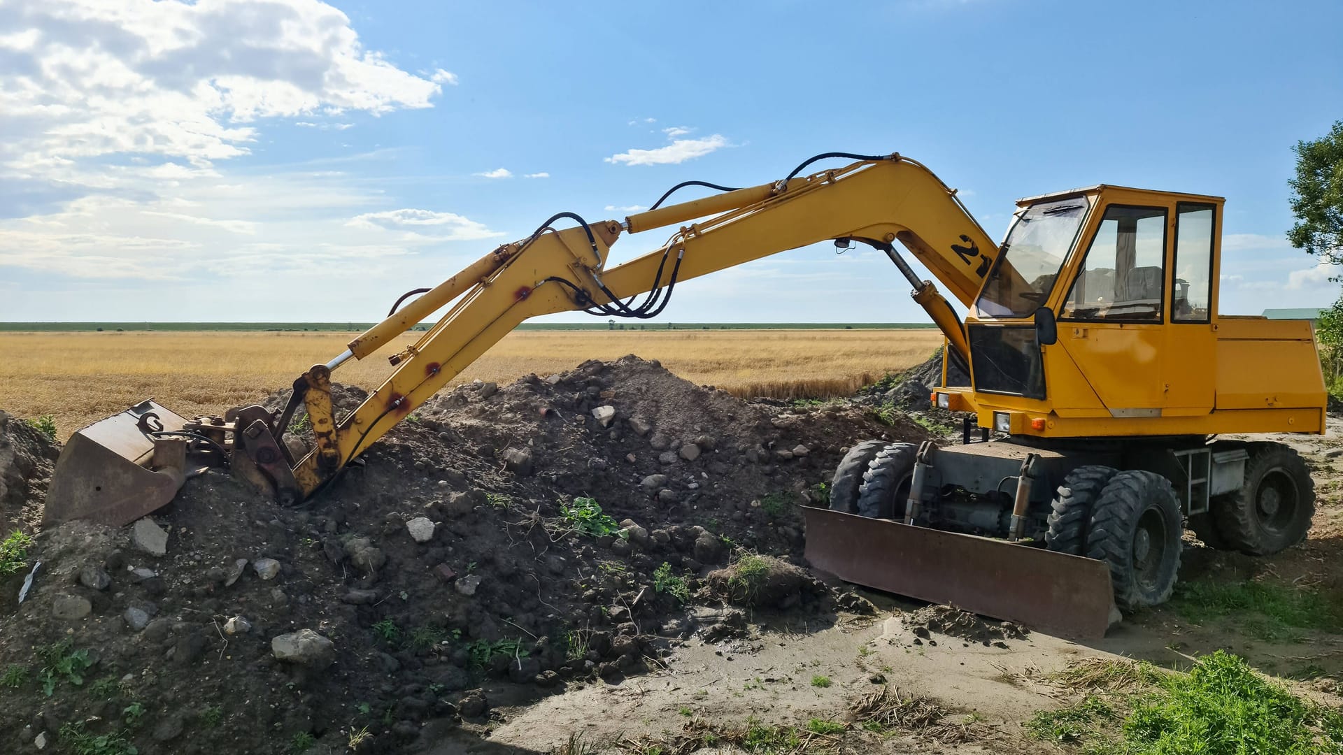 Ein Bagger auf einem Feld (Symbolbild): Die Bauarbeiten ruhen nun erst einmal, bis Mitte 2024 wird archäologisch geforscht.