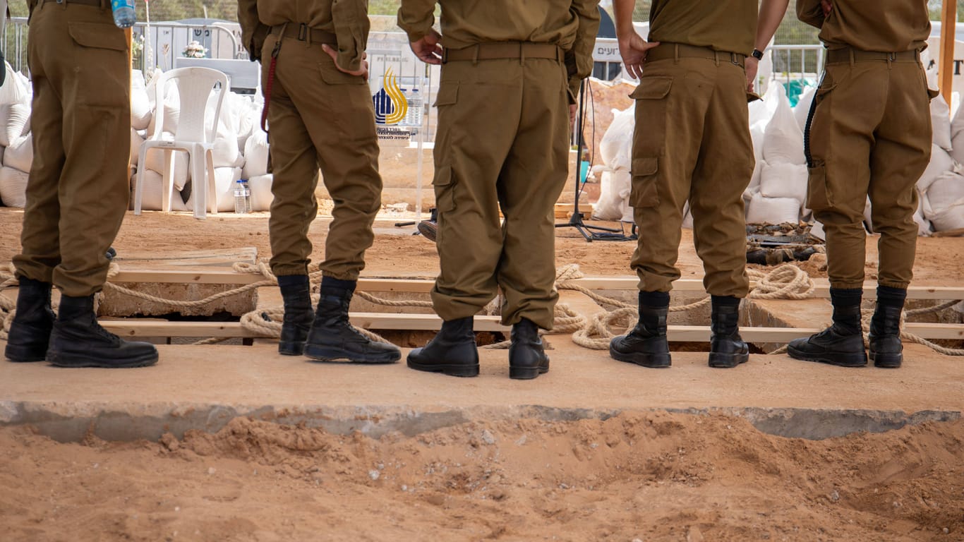 Angehörige der israelischen Armee lassen die Särge der fünfköpfigen Familie in den Boden.