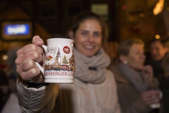Eine Frau mit Nürnberger Glühwein in der Hand (Symbolbild): Das Geheimnis um den Glühweinpreis ist jetzt gelüftet.