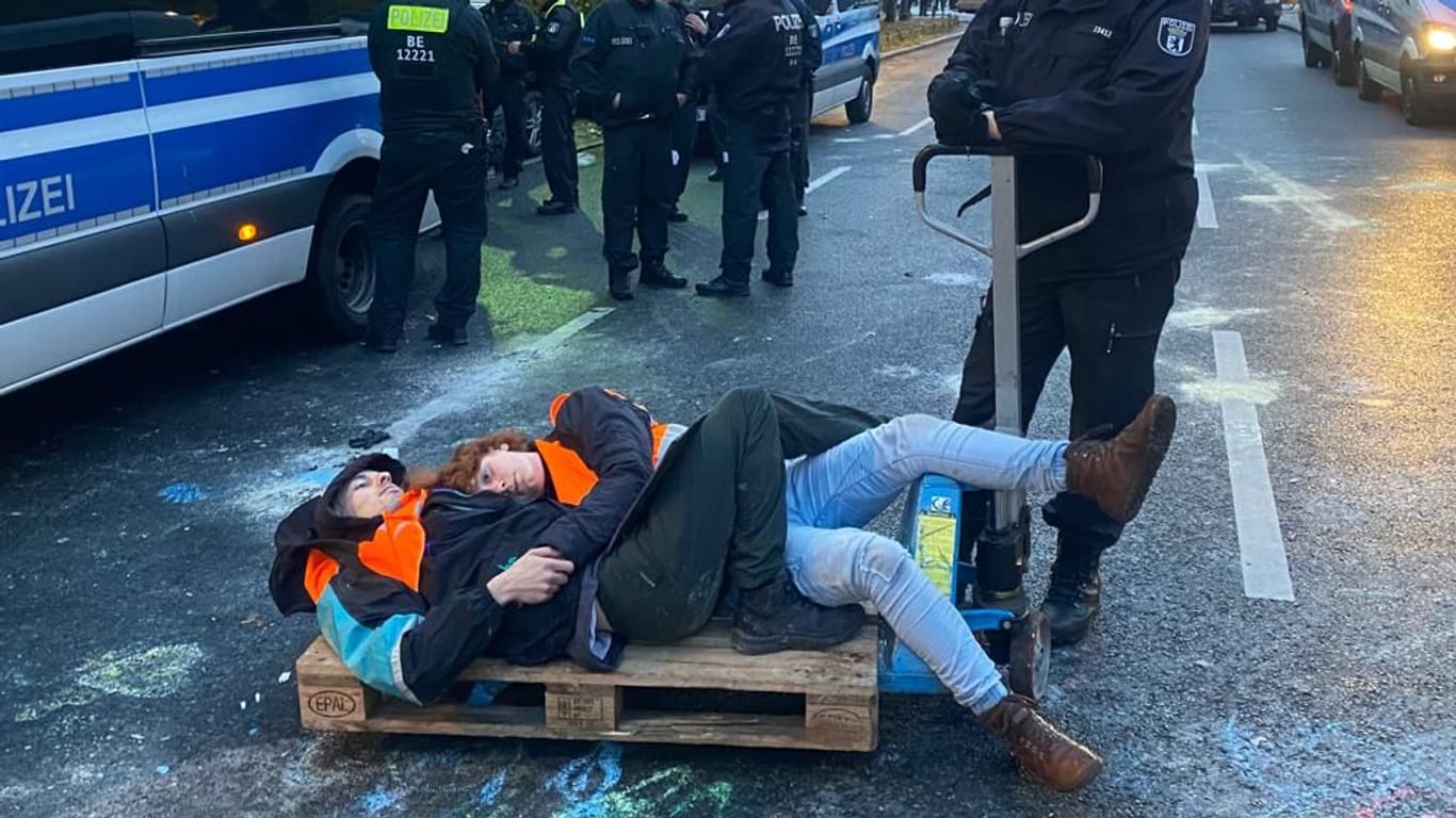 Ein Polizist transportiert Klimaaktivistinnen auf einer Europalette ab.