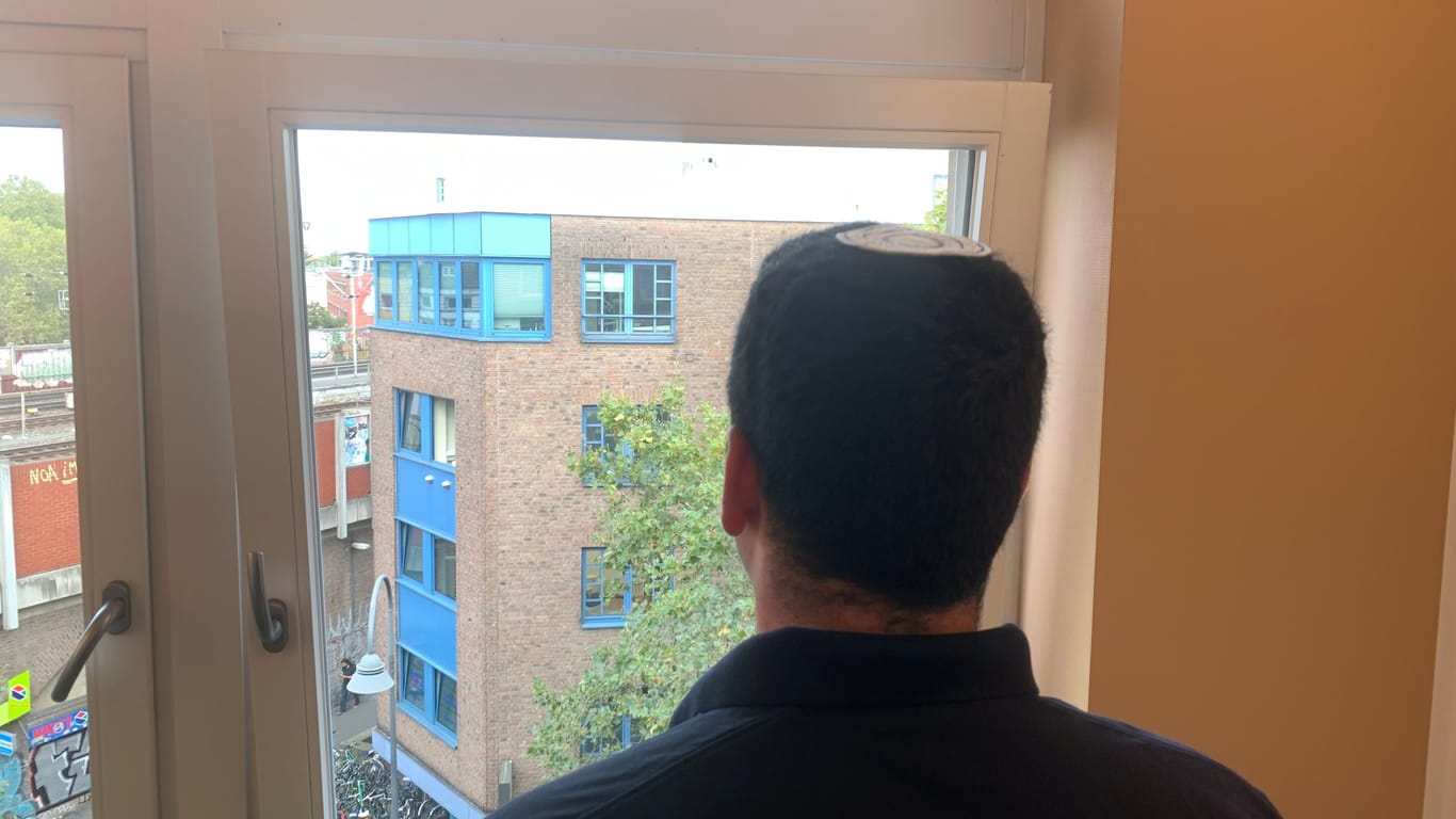 Israeli Avinoam blickt aus einem Fenster auf eine Kölner Straße. Er will für sein Land kämpfen.