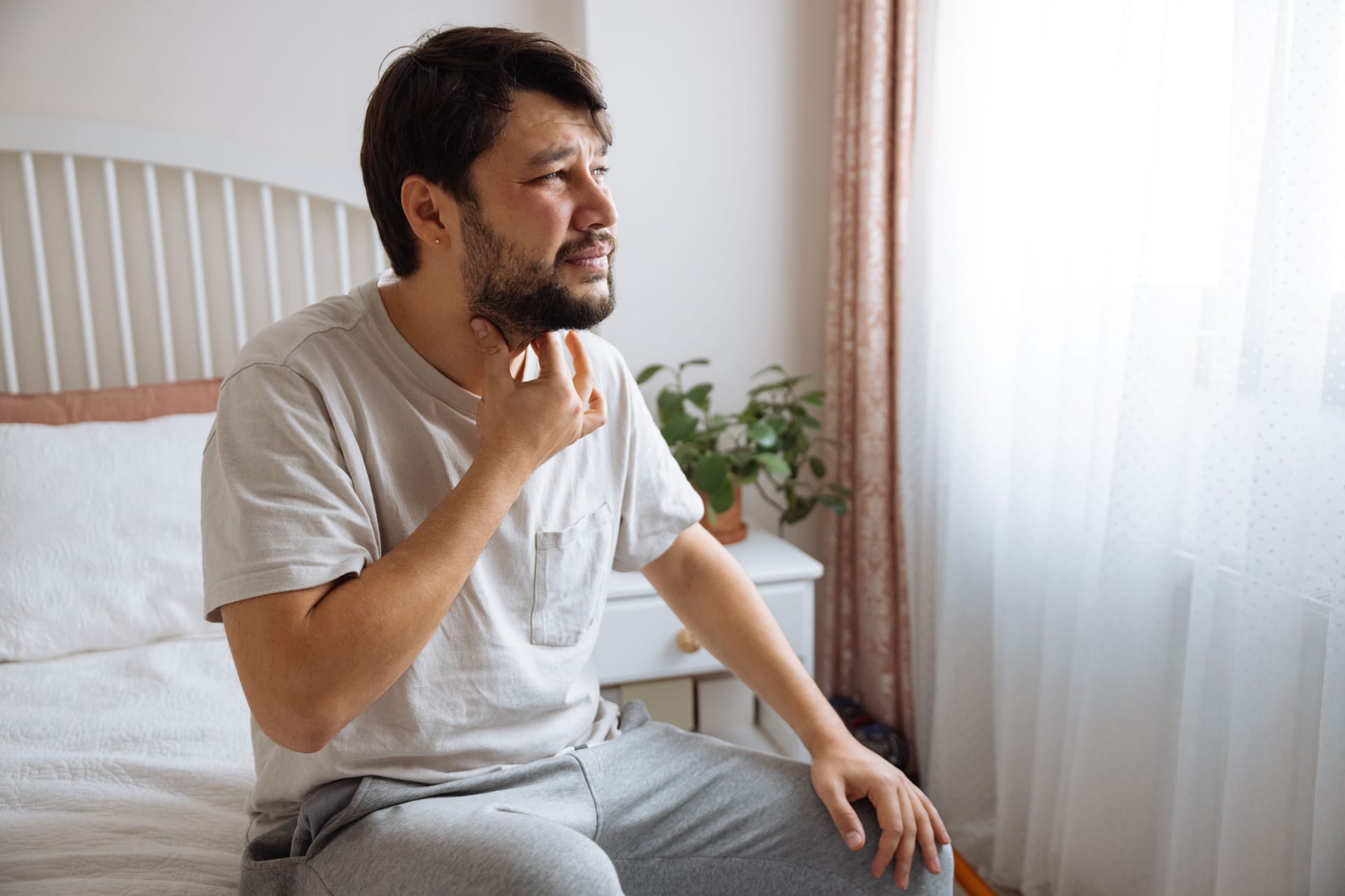 Ein Mann fasst sich an den Hals: Lässt sich eine Art Kloß im Hals verspüren, kann das verschiedene Ursachen haben. Manchmal hängt auch die Psyche mit den Beschwerden zusammen.