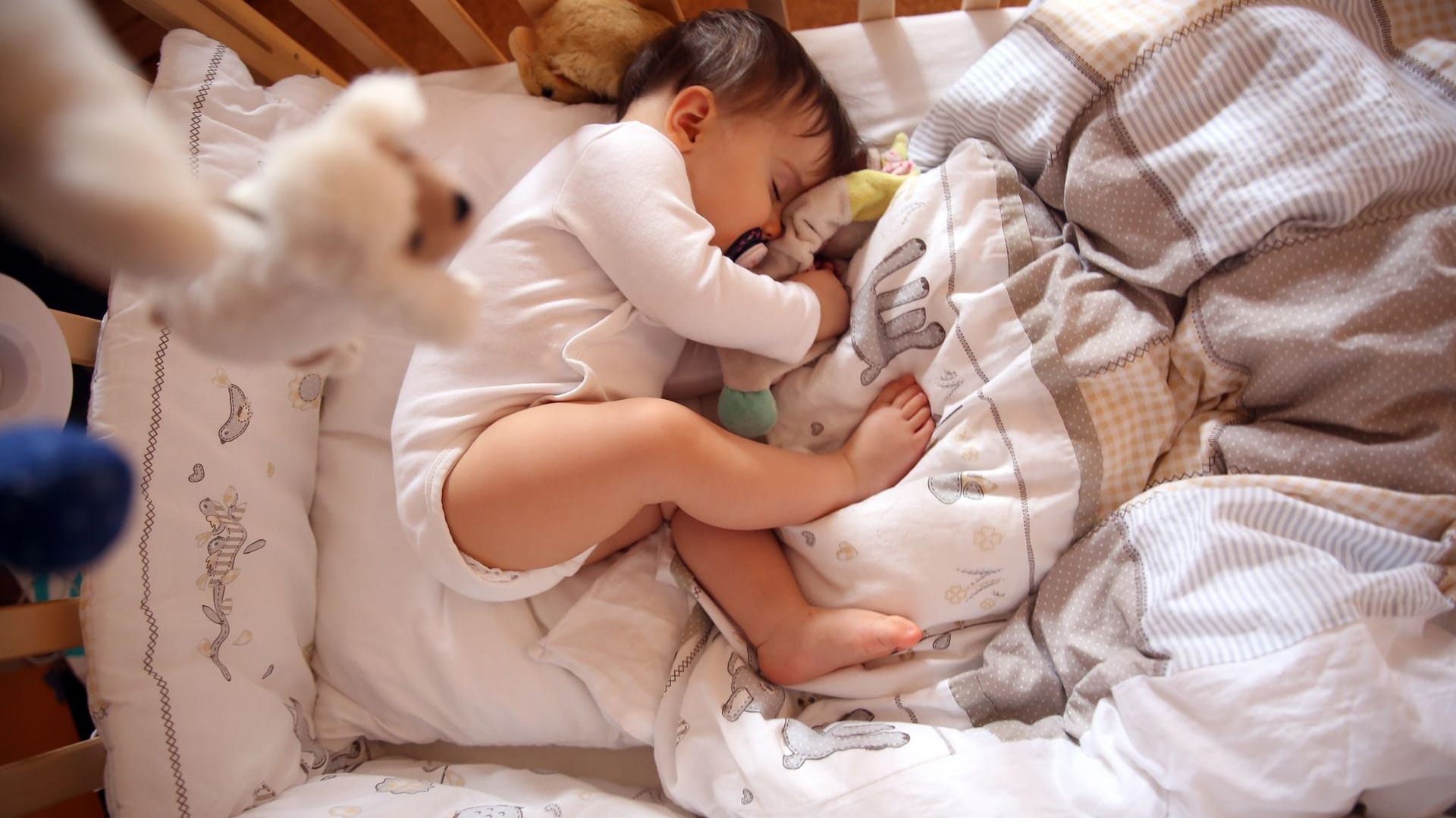 Ein Baby schläft in einem Gitterbettchen für Kinder.