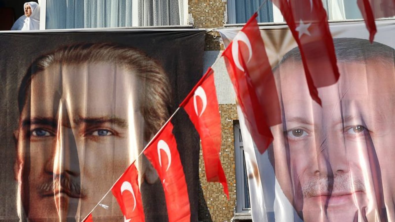 Istanbul: Eine Frau blickt aus einem Fenster hinter einem Banner des türkischen Staatsgründers Atatürk (l) und des türkischen Präsidenten Erdogan.