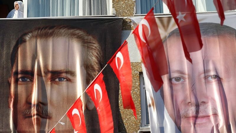 Istanbul: Eine Frau blickt aus einem Fenster hinter einem Banner des türkischen Staatsgründers Atatürk (l) und des türkischen Präsidenten Erdogan.