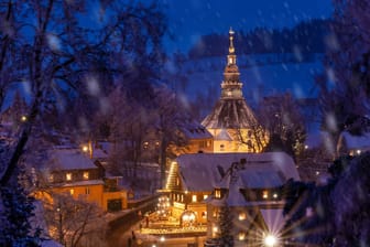 Festlich beleuchtet in der Blauen Stunde sind die Bergkirche und Häuser im leicht verschneiten weihnachtlichen Ort Seiffen im Erzgebirge.