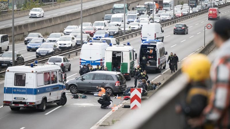 Ein Aktivist klebt während einer Straßenblockade der Klimaschutzgruppe "Letzte Generation" auf der A100 Richtung Neukölln nahe des Hohenzollerndamms unter einem Auto.