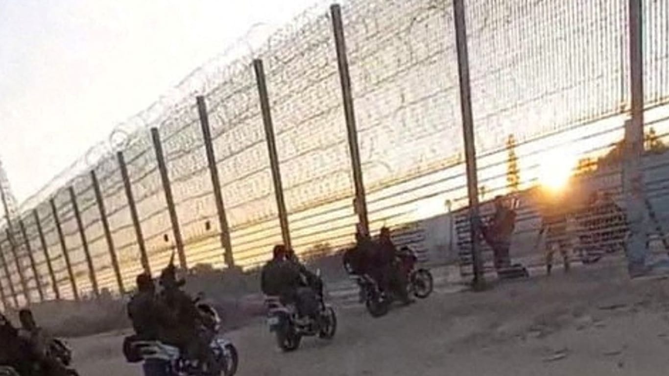 Palästinensische Kämpfer durchdringen den Grenzzaun.