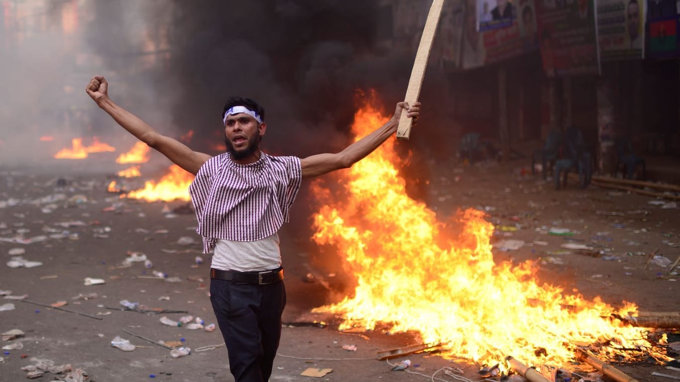 Demonstrant steht während Ausschreitungen in Dhaka vor einer brennenden Barrikade: Zu dem Protest für faire und freie Wahlen kamen über 100.000 Menschen.