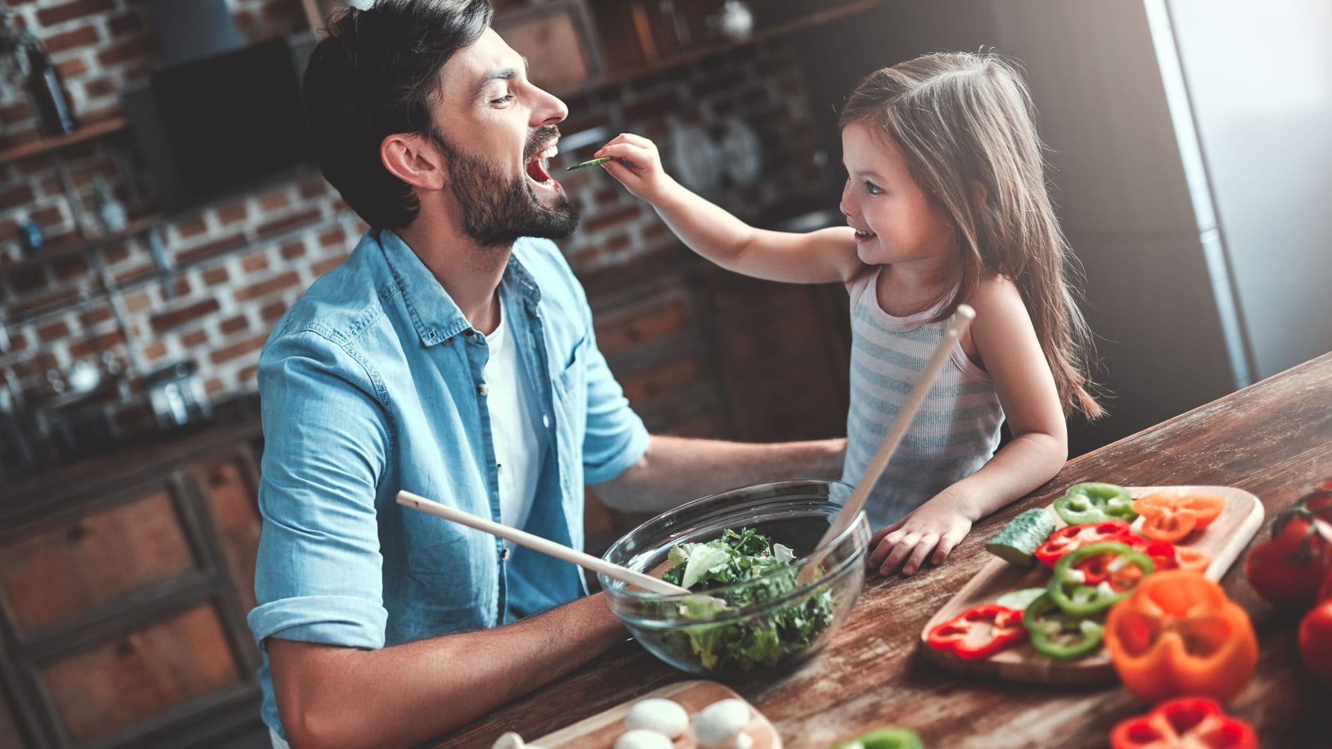 Vater und Tochter bereiten einen Salat zu.