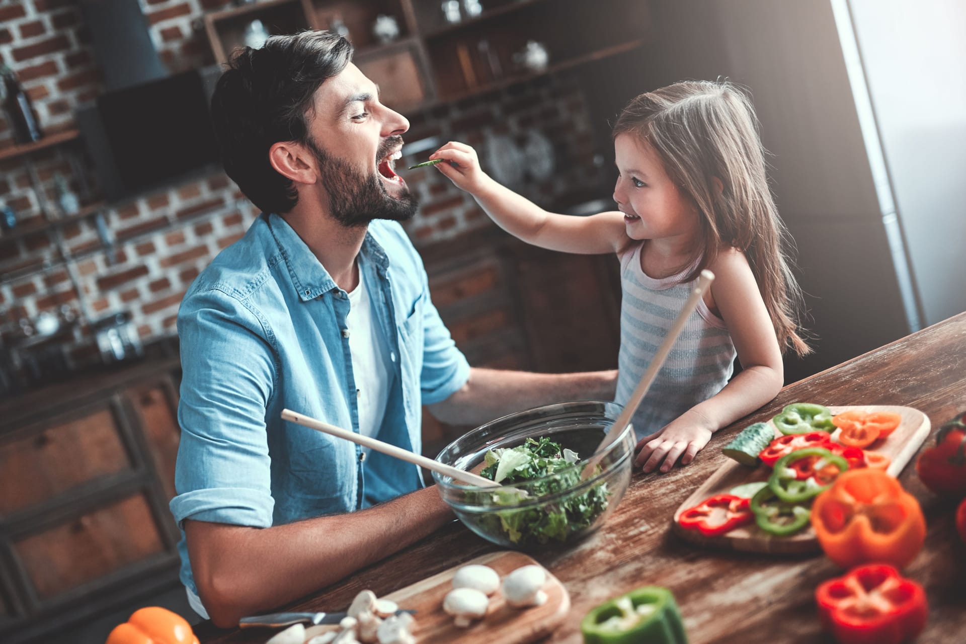 Vater und Tochter bereiten einen Salat zu.