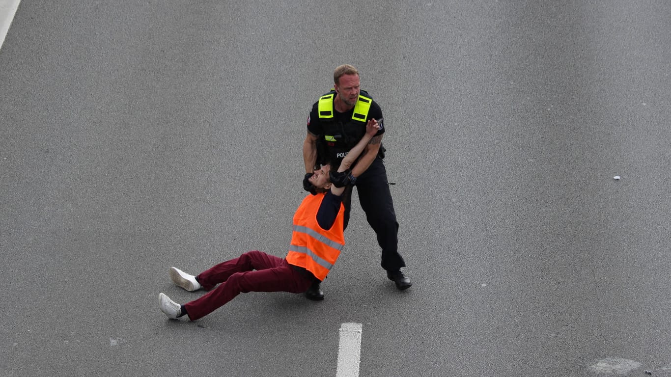 Ein Polizist zieht einen Klimaaktivisten von der A100 (Archivbild):