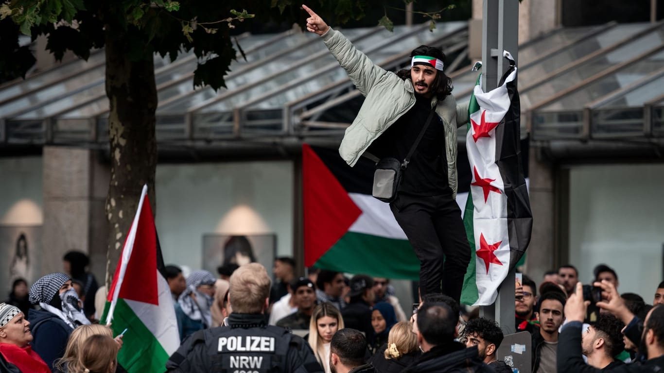 Bochum: Ein Teilnehmer einer pro-palästinensischen Demonstration hängt eine Fahne an einen Mast.
