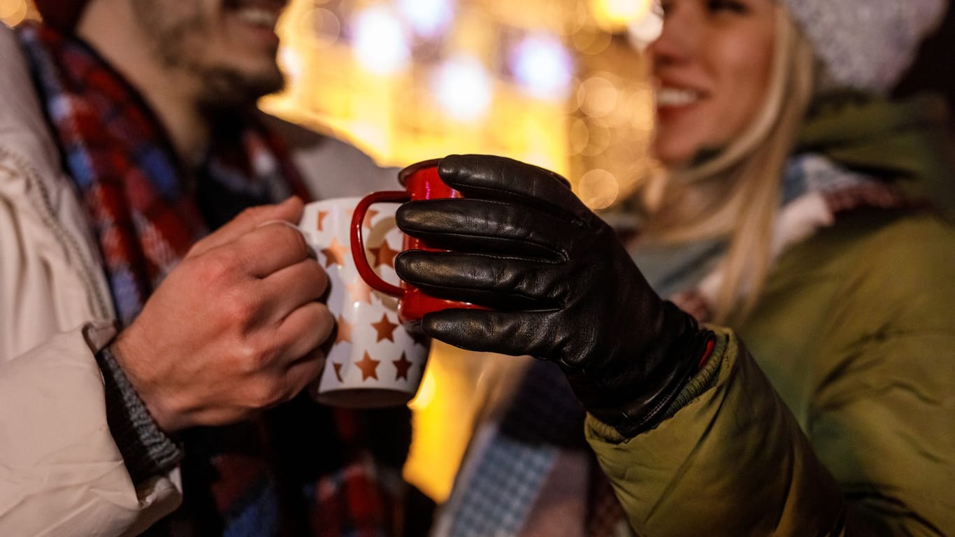 Weihnachtsmarktbesucher stoßen mit Glühwein an: Das Getränk wird traditionell in der Adventszeit getrunken.