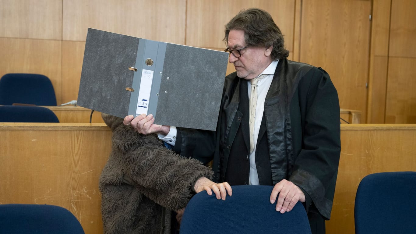 Zum Beginn des zweiten Prozesses gegen die "Sektenchefin aus Hanau" verdeckt einer ihrer Verteidiger das Gesicht seiner Mandantin mit einem Aktenordner (Archivfoto).