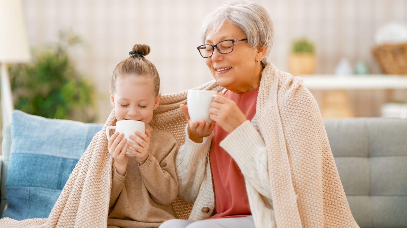 Ältere Frau trinkt mit ihrer Enkelin einen Tee.