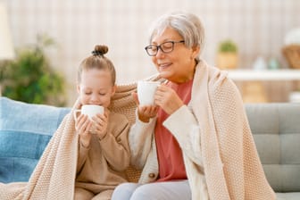 Ältere Frau trinkt mit ihrer Enkelin einen Tee.