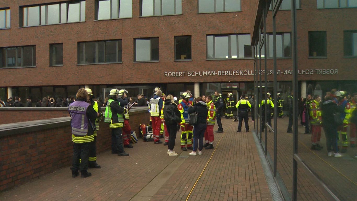 Einsatzkräfte der Feuerwehr vor dem Robert-Schuman-Berufskolleg: Feuerwehrleute durchlüfteten das Gebäude.