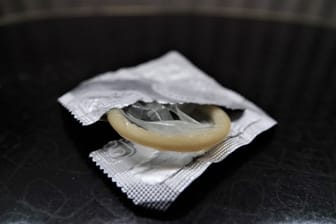 Eine geöffnete Kondompackung liegt auf einem Nachttisch