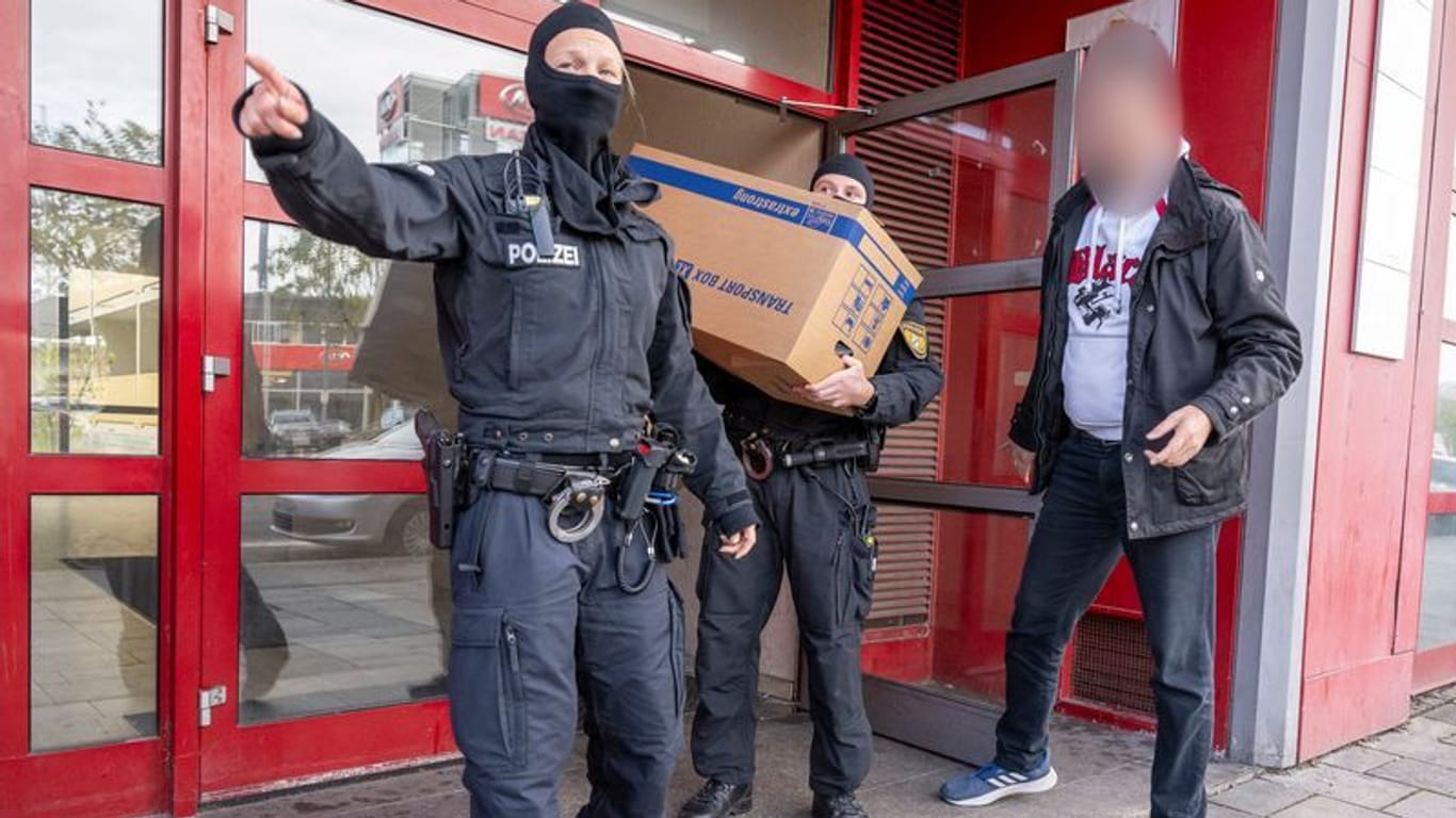 Polizisten transportieren aus dem Gebäude der Islamischen Vereinigung Bayern in München Kisten ab.