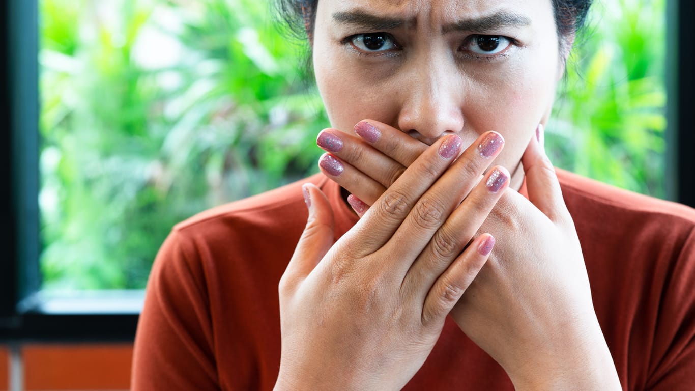Eine Frau bedeckt ihren Mund mit den Händen: Den ein oder anderen Trick, um Schluckauf loszuwerden, kennen die meisten.