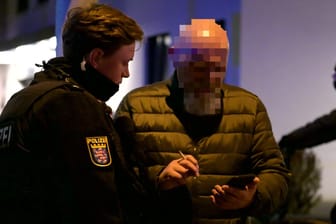 Ein Frankfurter Polizist schaut dabei zu, wie ein Gaffer Fotos der Unfallstelle von seinem Handy löscht.