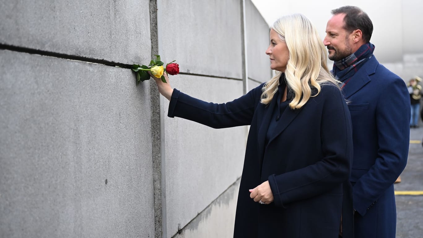 Der norwegische Kronprinz Haakon und seine Frau Kronprinzessin Mette-Marit stecken bei der Zentralen Gedenkveranstaltung des 34. Jahrestags des Mauerfalls an der Gedenkstätte Berliner Mauer Rosen in die Mauer.