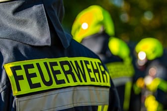 Feuerwehrleute stehen zusammen (Symbolbild): In Hamburg löschte die Feuerwehr ein in Brand geratenes Haus.