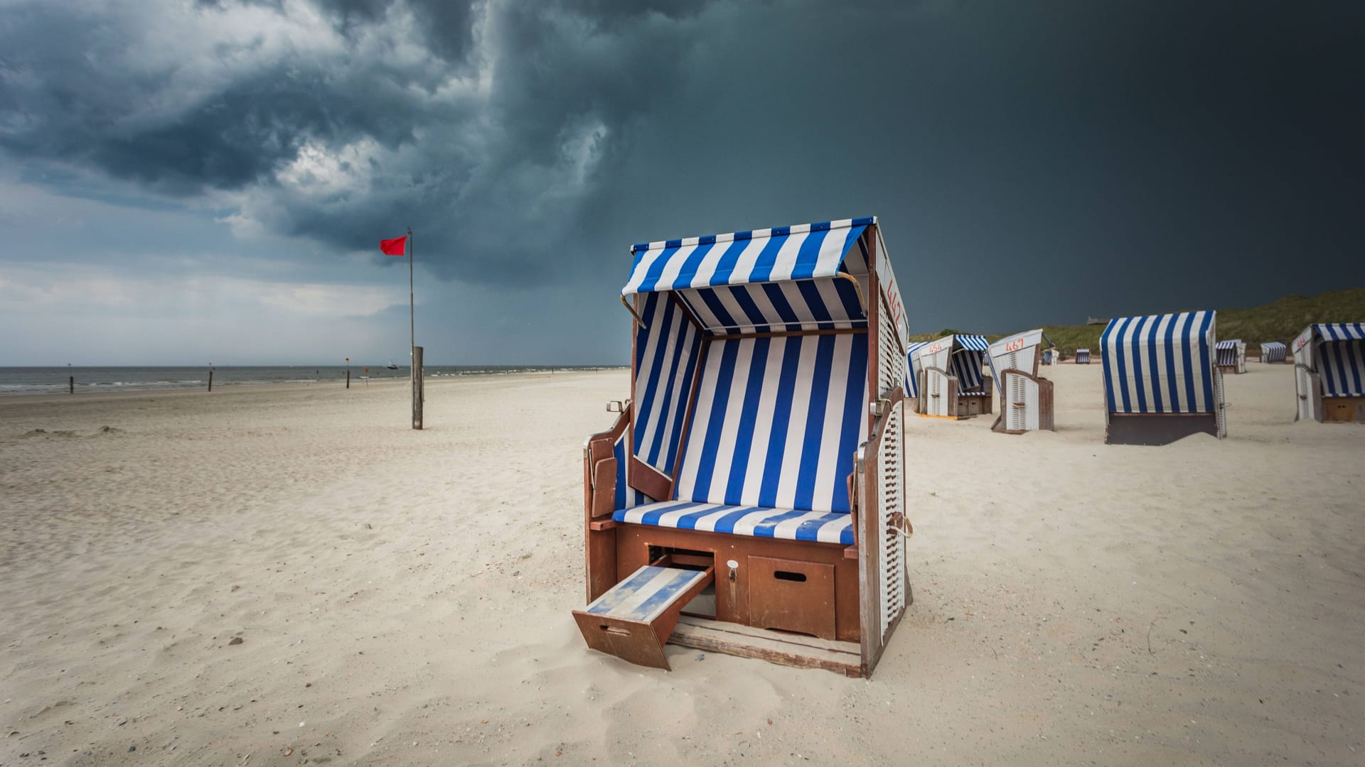 Düstere Gewitterwolken über dem Nordstrand von Norderney (Archivbild): Der deutsche Wetterdienst warnt vor Gewitter und schweren Sturmböen an der Nordsee.