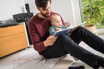 Vater liest seinem Kind vor: Elterngeld steht künftig weniger Familien zu.