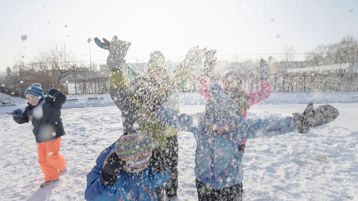 Kinder spielen im Schnee (Symbolfoto): In Bayern wird es in manchen Regionen am Wochenende weiß.