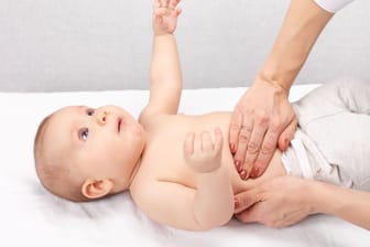Eine Ärztin tastet den Bauch eines Babys ab