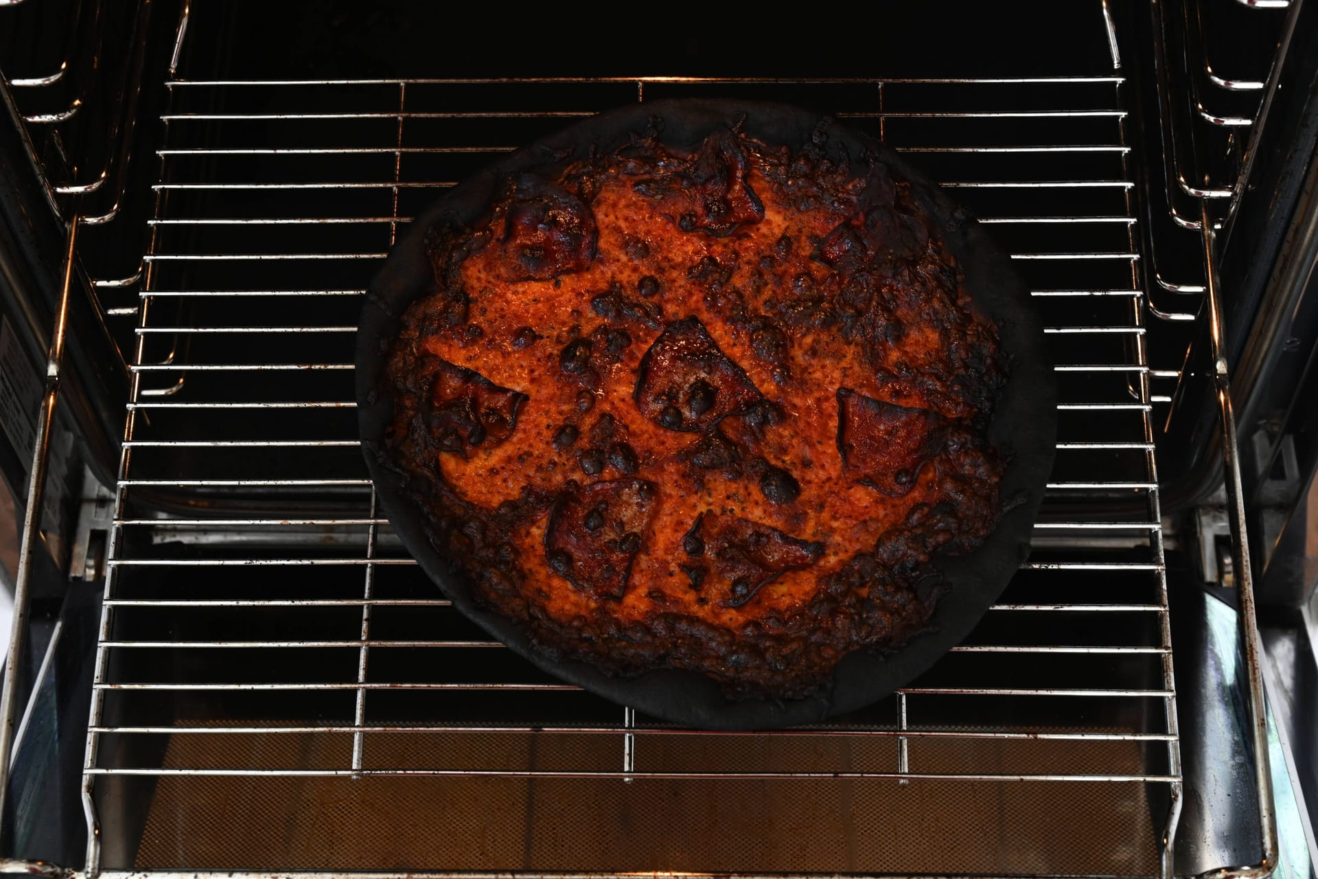 Eine verbrannte Pizza liegt in einem Backofen (Symbolbild).