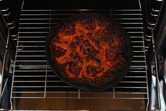 Eine verbrannte Pizza liegt in einem Backofen (Symbolbild).