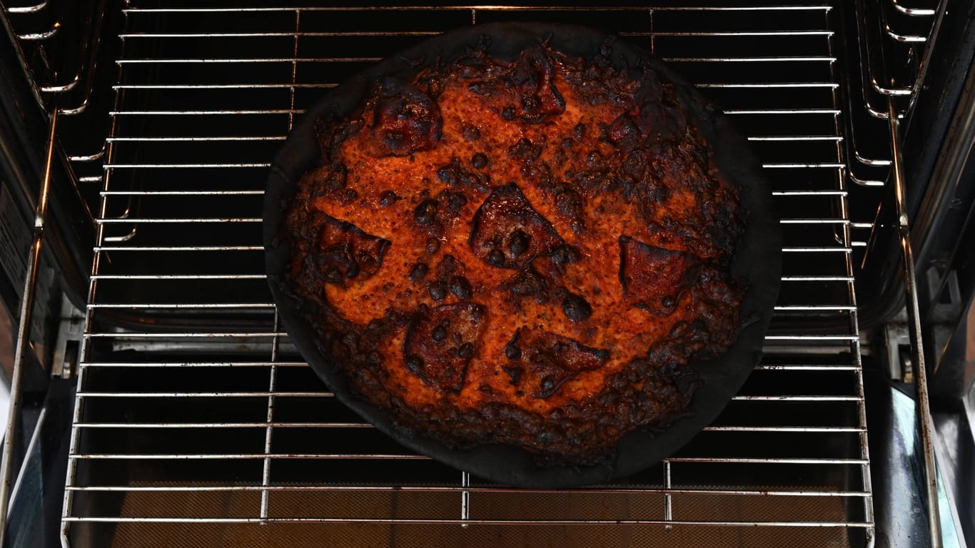 Eine verbrannte Pizza liegt in einem Backofen (Symbolbild).