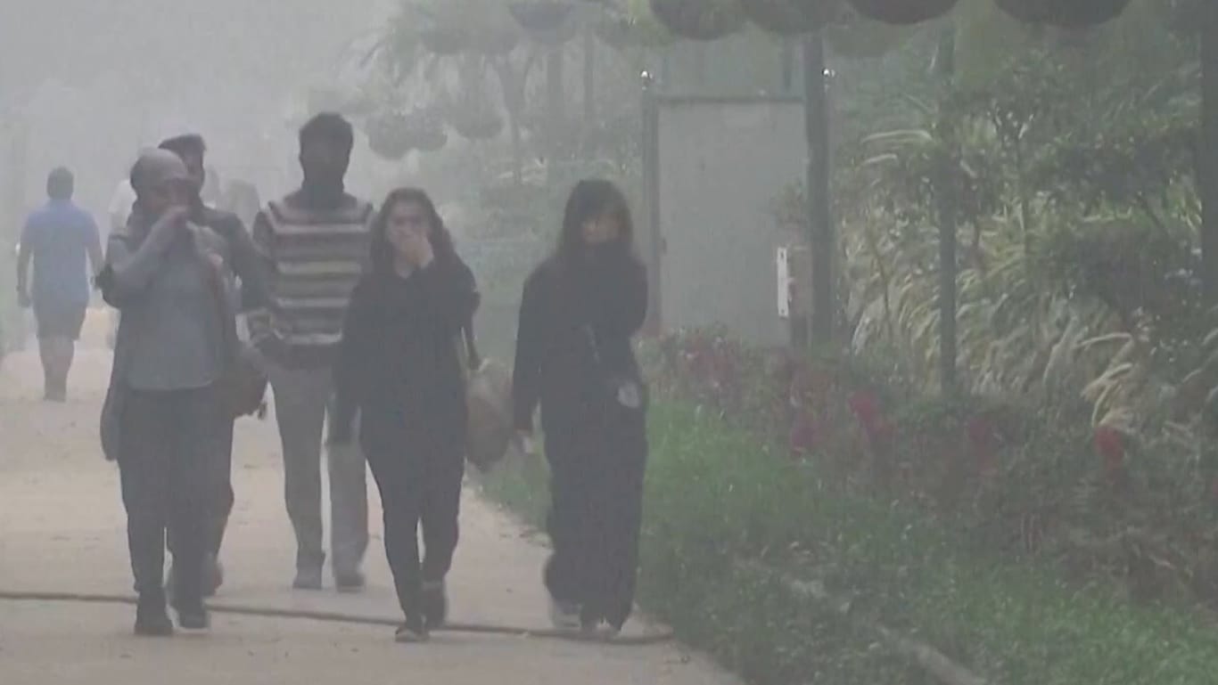 Menschen halten sich die Hand vors Gesicht: Seit Tagen liegt eine gewaltige Smog-Wolke über der Stadt.