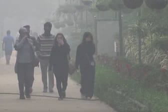 Menschen halten sich die Hand vors Gesicht: Seit Tagen liegt eine gewaltige Smog-Wolke über der Stadt.