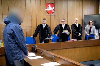 Der Angeklagte (l) steht vor Prozessbeginn vor dem Vorsitzenden Richter Volker Stronczyk (3.v.r.).