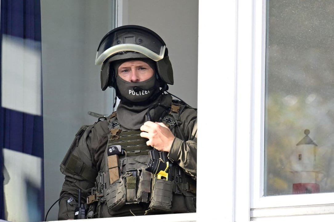 Ein vermummter Polizist steht in einem Fenster der Stadtteilschule Blankenese: Dort bedrohte ein Junge eine Lehrerin.