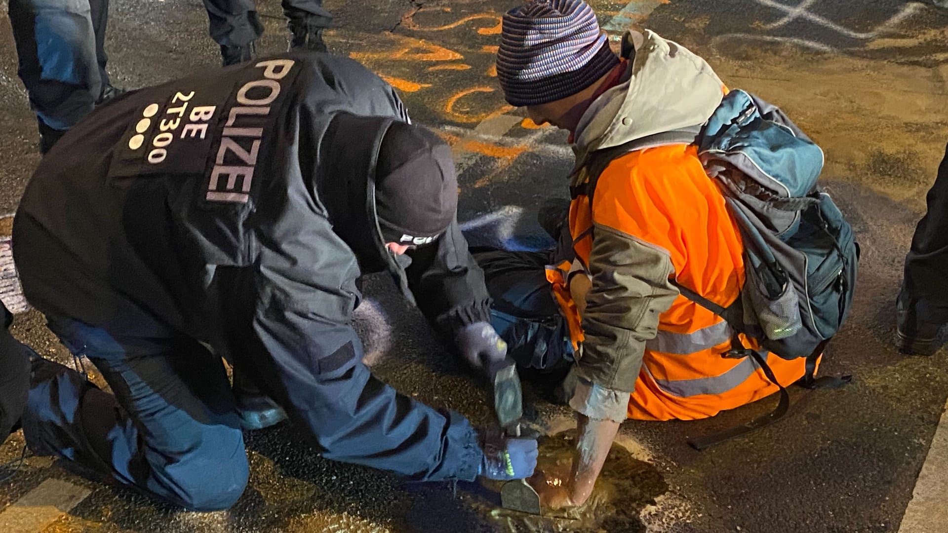 Arbeit mit Werkzeug: Ein Polizist löst die festgeklebte Hand eines Klimaklebers mit Hammer und Meißel.